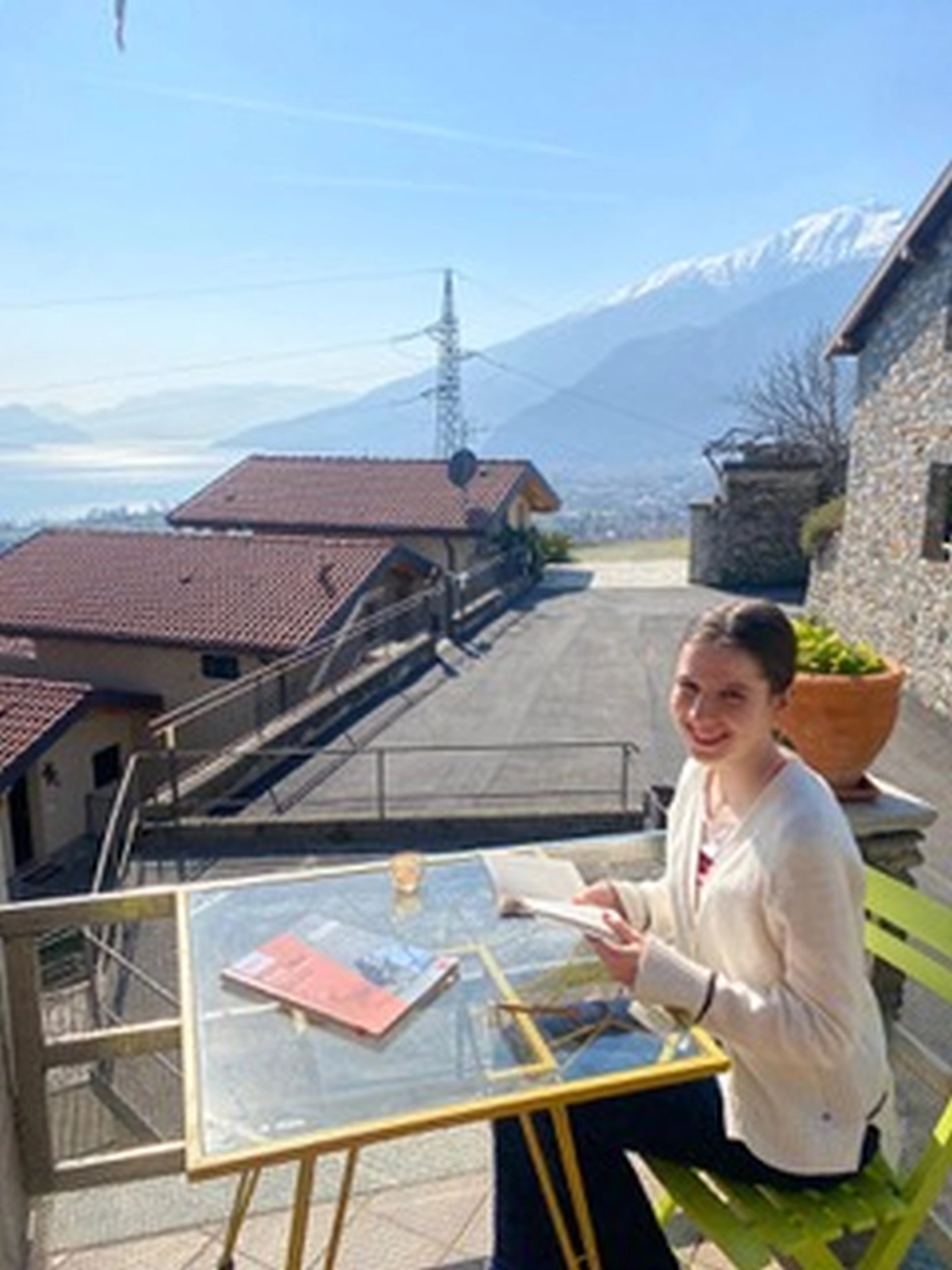 SprachHaus Bamberg - uomo che studia un libro con vista sulle montagne e sul lago sullo sfondo